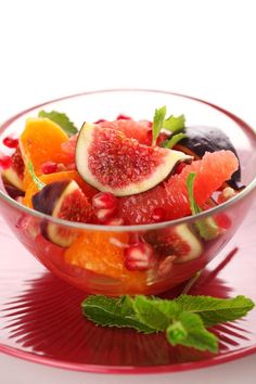 a glass bowl filled with fruit on top of a red plate