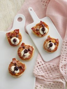 mini pizzas with bacon, cheese and black olives arranged on a white platter