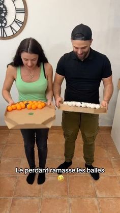 the man and woman are holding boxes with oranges in them while standing next to each other