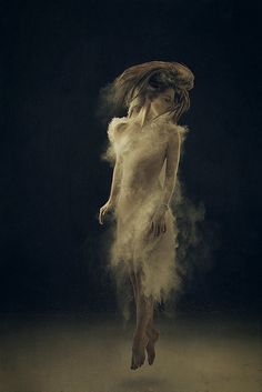 a woman is standing in the dust with her hair blowing