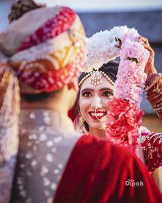 a woman is dressed in red and white with flowers on her head as she smiles at the camera