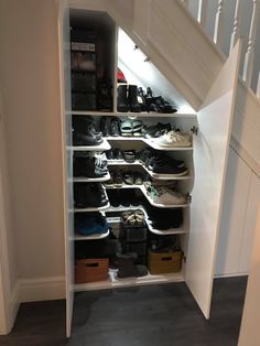 an open closet under the stairs with shoes on it