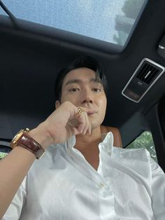 a man sitting in the back seat of a car holding his hand up to his mouth