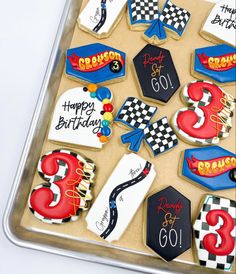 decorated birthday cookies in the shape of numbers and race cars on a tray with writing