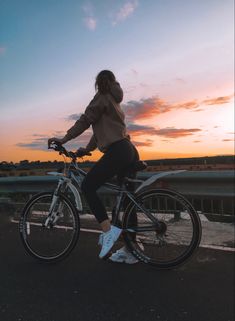 a woman is riding her bike at sunset