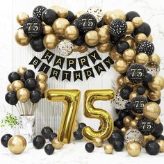 a black and gold balloon arch with the number 75 on it, surrounded by balloons