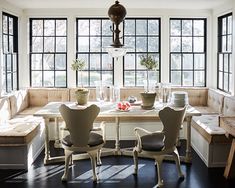 a dining room table with four chairs and a bench in front of the window,