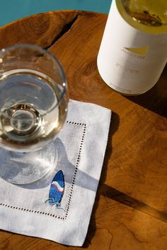 a glass of water sitting on top of a wooden table next to a wine bottle