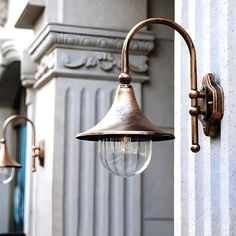 an old fashioned light hanging from the side of a building next to a white door