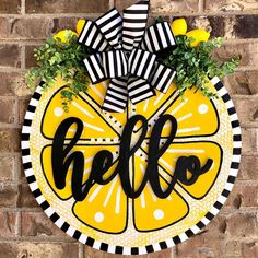 a yellow and black door hanger with the word hello on it, next to a brick wall