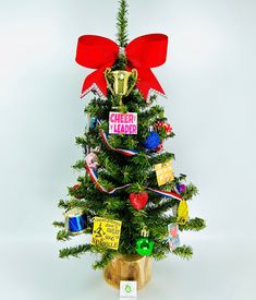 a small christmas tree with red bow and cheerleader tags on it's top