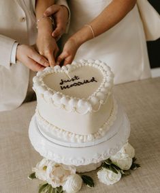 a newly married couple cutting their wedding cake with the words just married written on it