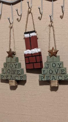 three christmas decorations hanging from hooks on a wall with the words joy, love, and peace