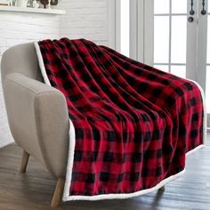 a red and black plaid blanket sitting on top of a chair next to a white brick wall