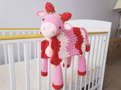 a crocheted cow hanging from the side of a crib