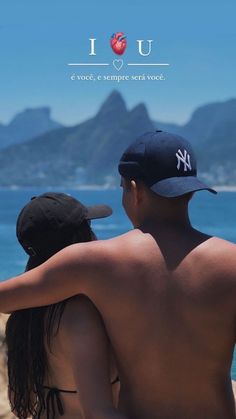 a man and woman sitting on the beach looking at the ocean