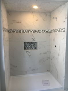 a bathroom with white marble walls and flooring in the shower area, along with black and white tiling