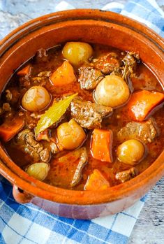 a bowl filled with meat and vegetables on top of a blue checkered table cloth