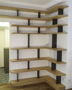 an empty room with some shelves on the wall and one shelf in the middle that has black metal bars sticking out of it