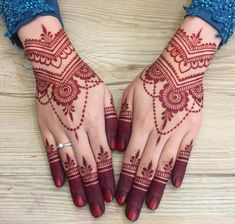 two hands with henna tattoos on them, one is red and the other is white