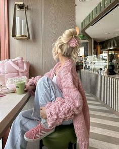 a woman sitting on top of a green stool in front of a counter next to a window