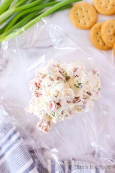 a plastic bag filled with crab salad next to crackers and green onions on a table