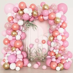 a pink and gold balloon arch is surrounded by balloons