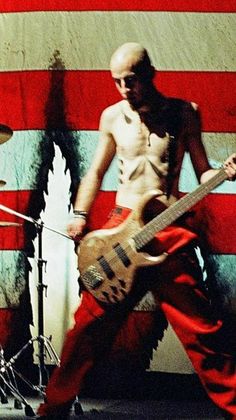 a man with an electric guitar standing in front of the american flag painted on a wall