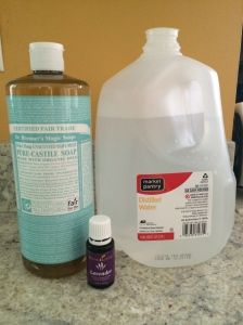 a bottle of soap next to a container of water and an essential oil on a counter