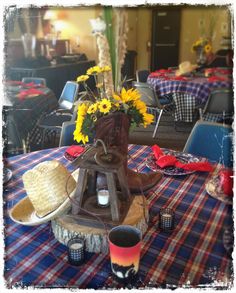 the table is set with sunflowers and cowboy hats on it, along with other decorations