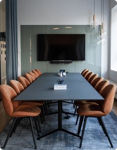 a long table with chairs and a television mounted on the wall in front of it