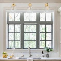 a kitchen with white cabinets and an island in front of a window that is open to the outside