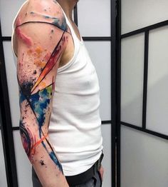 a man wearing a white tank top with colorful ink splattered on his arm