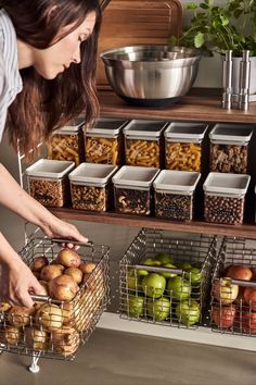 a woman picking up apples from a shelf