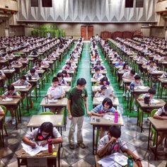 many students are sitting at desks in a classroom with green walls and flooring