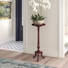 a potted plant sitting on top of a wooden stand in a living room next to a doorway