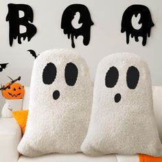 two white pillows with black eyes and ghost faces on them, sitting next to each other