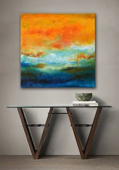 an abstract painting hangs on the wall above a glass table