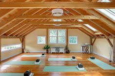 there are many yoga mats on the floor in this large room with wood beams and windows