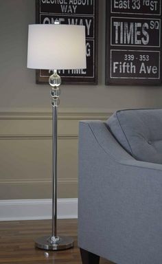 a lamp that is on top of a table in front of a couch and two framed pictures