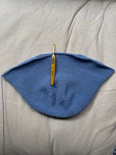 a crocheted blue piece of cloth on top of a white pillow