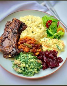 a white plate topped with meat, mashed potatoes and veggies