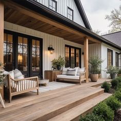 a porch with two couches on it and potted plants next to the doors