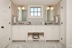 a white bathroom with double sinks and two mirrors on the wall next to each other