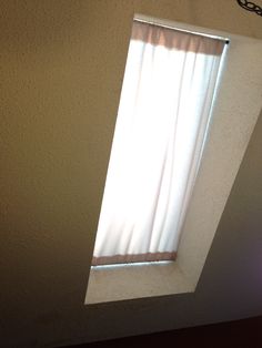 an open window on the side of a wall with white curtains and light coming through