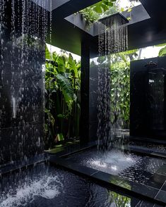 an outdoor shower with water flowing from it's sides and greenery in the background