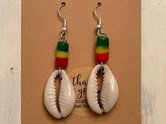 Offered are a pair of earrings featuring beads and cowrie shells. They measure about 2.25 inches long. Cowrie Shell Earrings For Gifts, White Shell-shaped Cowrie Shell Earrings, White Cowrie Shell Earrings, Handmade White Beaded Earrings For Vacation, Bohemian White Cowrie Shell Earrings, Unique Adjustable Beaded Earrings For Beach, Handmade Casual Beaded Earrings For Beach, Cowrie Shell Earrings, Reggae Bob Marley