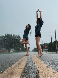 two girls jumping in the air on an empty road