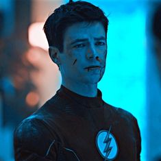 a young man dressed as the flash standing in front of a blue light with his mouth open