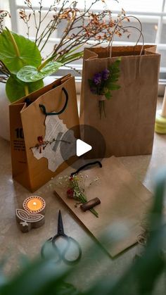 two brown bags with flowers on them sitting next to some scissors and other items in front of a window